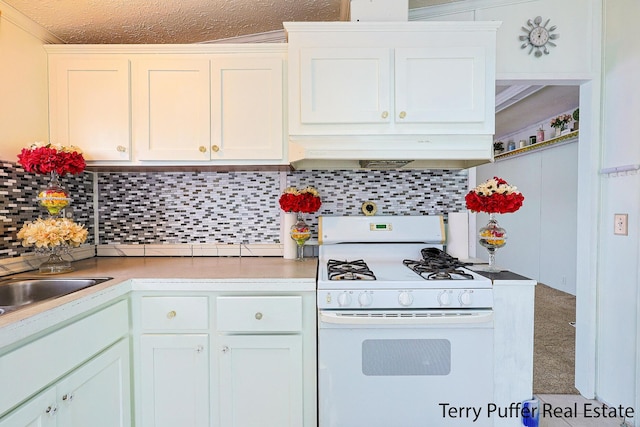 kitchen featuring range hood, white gas stove, decorative backsplash, and white cabinets