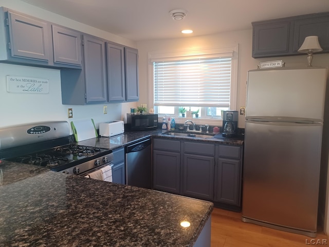 kitchen with appliances with stainless steel finishes, sink, and dark stone counters