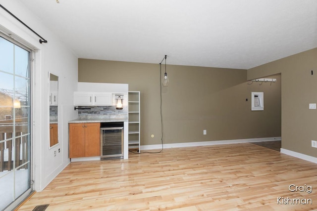 interior space featuring light wood-type flooring, decorative backsplash, baseboards, and beverage cooler