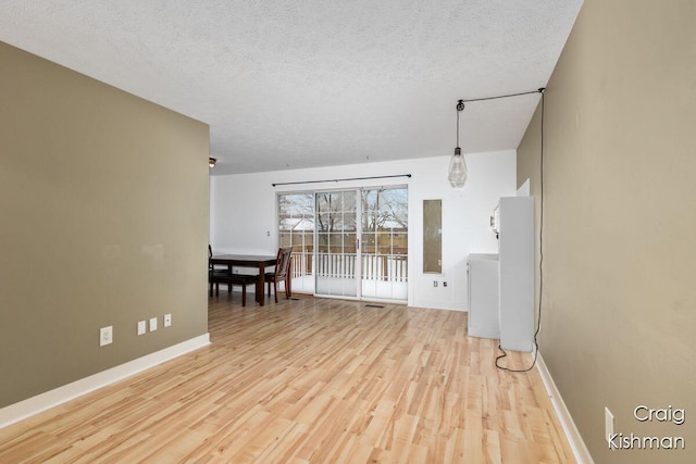 living room with baseboards, a textured ceiling, and light wood finished floors