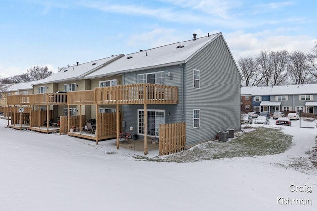 snow covered rear of property featuring central AC and a deck