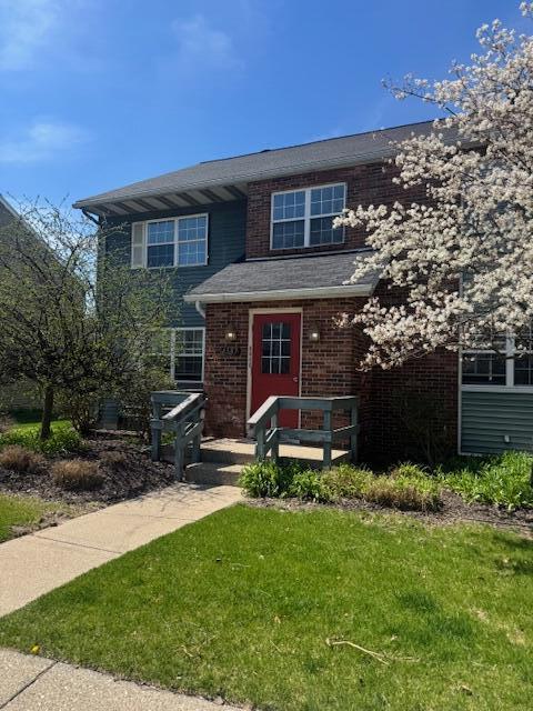 view of front facade with brick siding and a front lawn