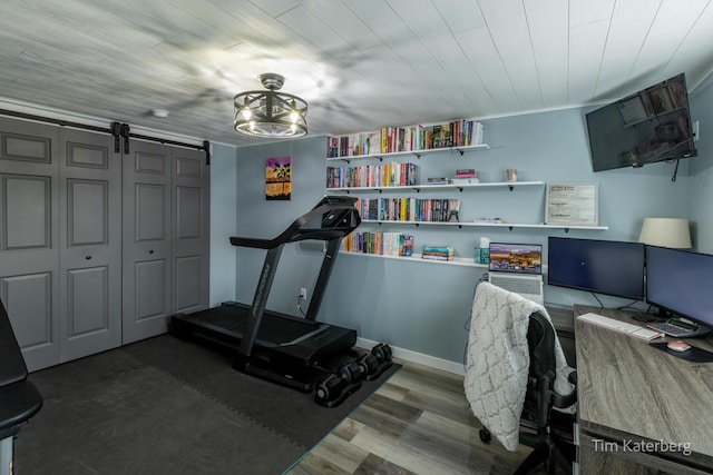 exercise room with hardwood / wood-style flooring and a barn door