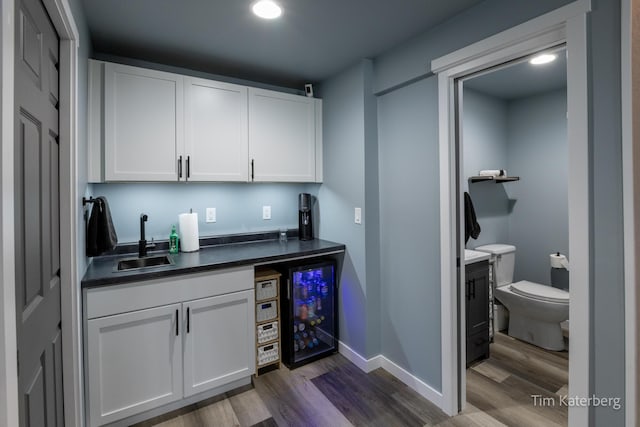 bar with sink, dark wood-type flooring, and white cabinets