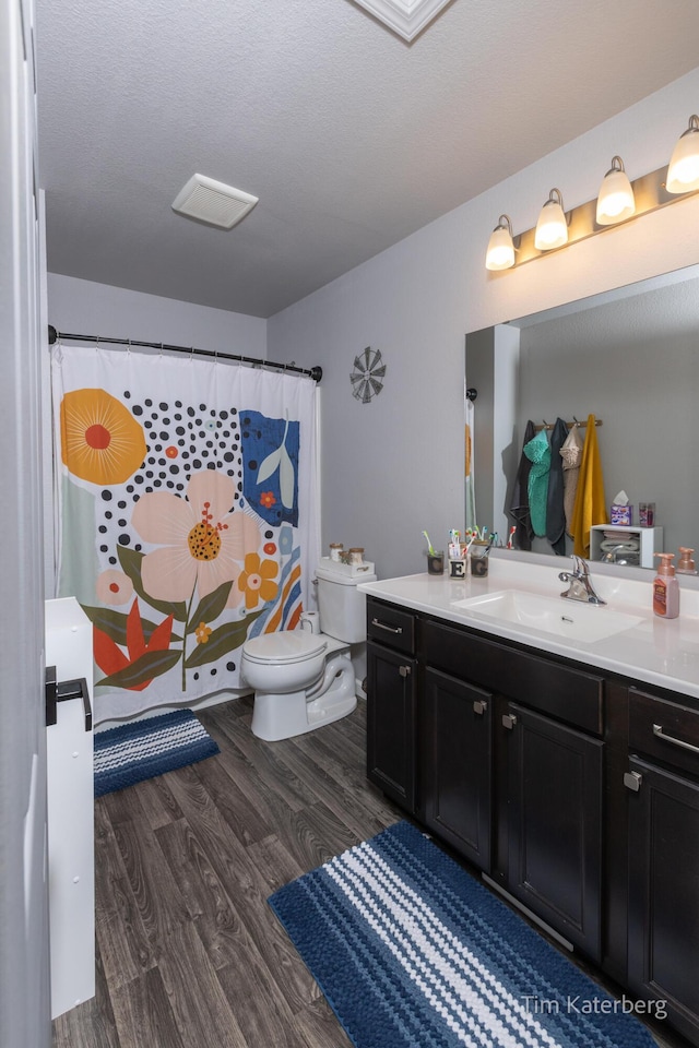 bathroom featuring vanity, hardwood / wood-style floors, a textured ceiling, and toilet