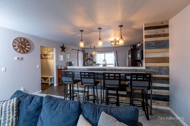 kitchen with a barn door, hanging light fixtures, and a textured ceiling