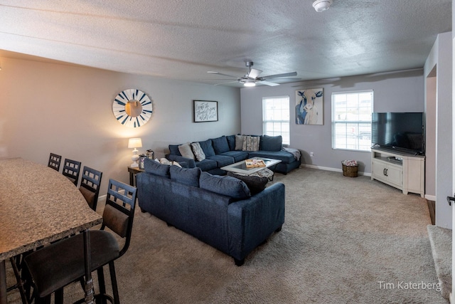 carpeted living room featuring ceiling fan and a textured ceiling