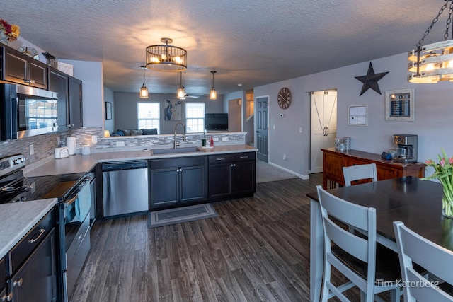 kitchen with appliances with stainless steel finishes, dark hardwood / wood-style floors, pendant lighting, sink, and backsplash