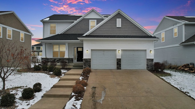 craftsman-style home with stone siding, an attached garage, and driveway