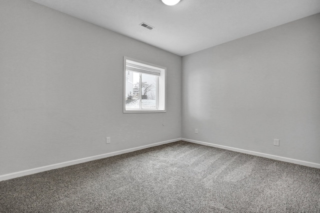 carpeted spare room featuring baseboards and visible vents