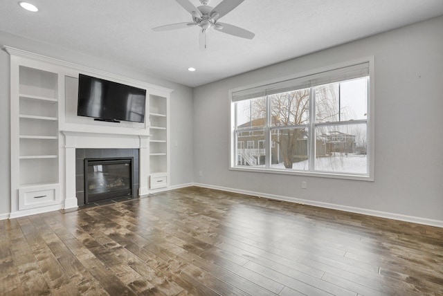 unfurnished living room with ceiling fan, dark wood-style flooring, a fireplace, and baseboards