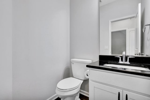 bathroom with toilet, baseboards, and vanity