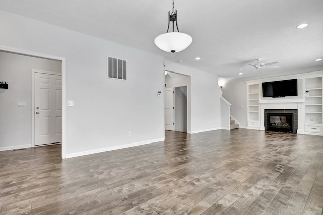 unfurnished living room with visible vents, stairway, baseboards, and wood finished floors