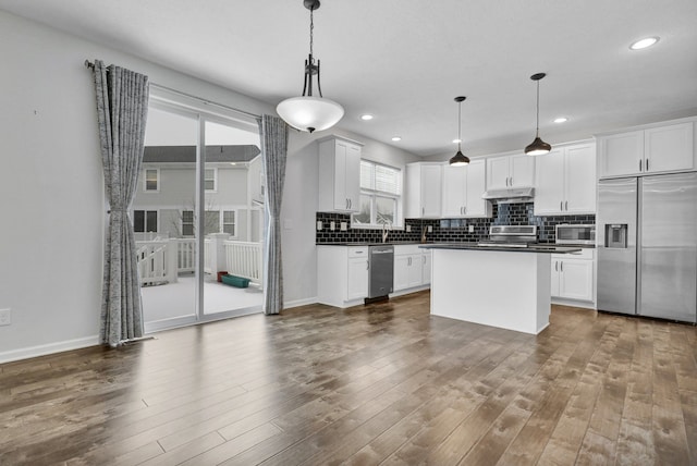 kitchen featuring appliances with stainless steel finishes, dark countertops, white cabinets, and pendant lighting