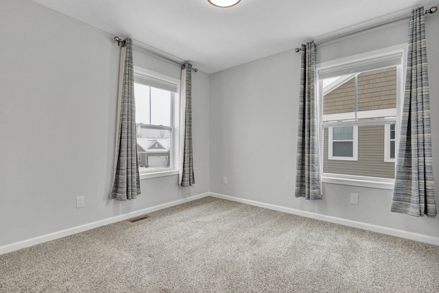 carpeted spare room featuring visible vents and baseboards