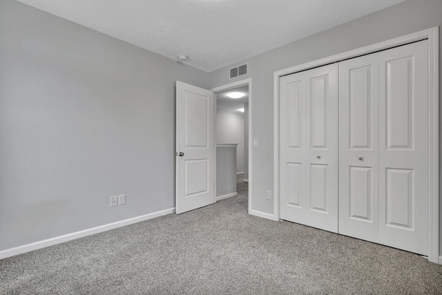 unfurnished bedroom with carpet floors, a closet, visible vents, and baseboards