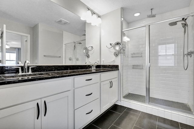 bathroom with double vanity, a stall shower, visible vents, and a sink