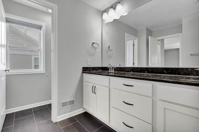 bathroom featuring double vanity, tile patterned flooring, visible vents, and a sink