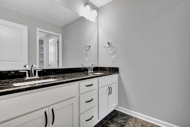 bathroom with double vanity, a sink, and baseboards