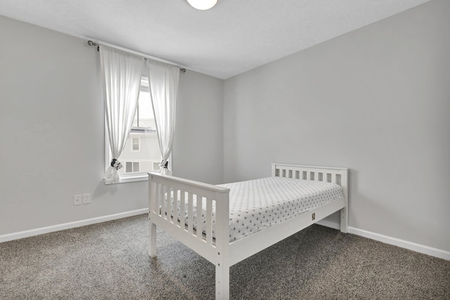 bedroom featuring dark carpet and baseboards