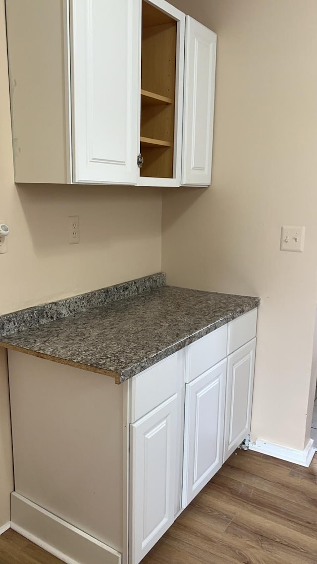 kitchen with hardwood / wood-style floors, white cabinets, and dark stone counters