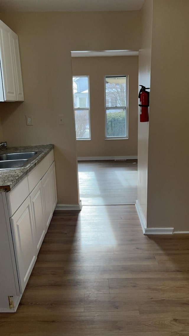 kitchen featuring white cabinetry, sink, dishwashing machine, and light wood-type flooring