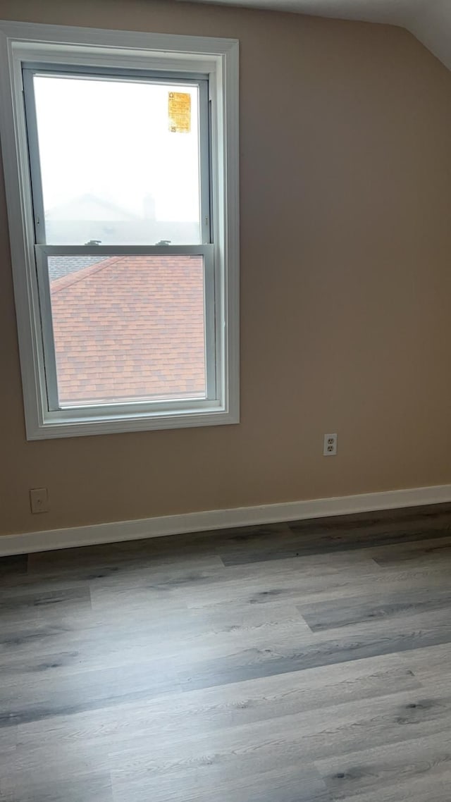 spare room with vaulted ceiling and light hardwood / wood-style flooring