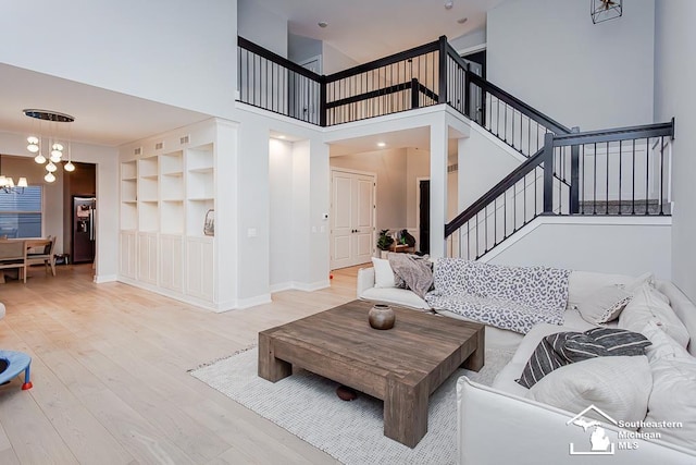 living room featuring an inviting chandelier, built in features, and light wood-type flooring