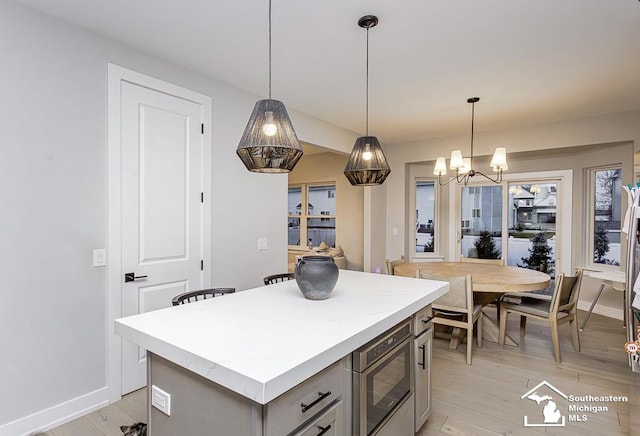 kitchen with pendant lighting, built in microwave, light hardwood / wood-style flooring, and a center island