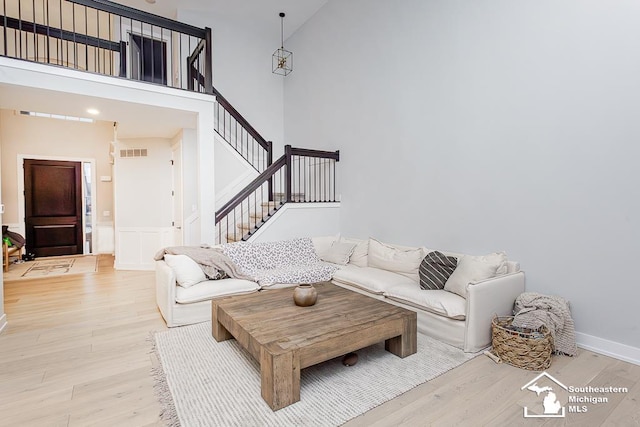 living room featuring a towering ceiling and light wood-type flooring