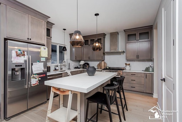 kitchen featuring tasteful backsplash, a center island, hanging light fixtures, stainless steel fridge, and wall chimney range hood