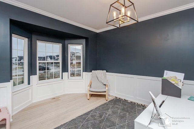 living area with hardwood / wood-style flooring, ornamental molding, and a chandelier