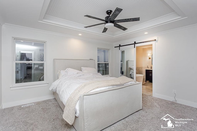 bedroom featuring a barn door, ornamental molding, and a tray ceiling