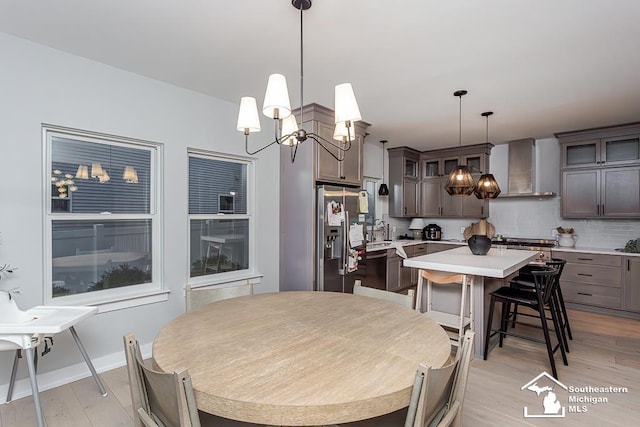 dining area with sink, light hardwood / wood-style floors, and a notable chandelier