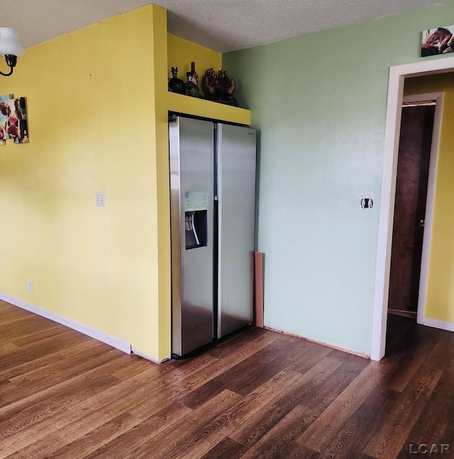 unfurnished bedroom featuring dark wood-type flooring, stainless steel fridge, and a textured ceiling