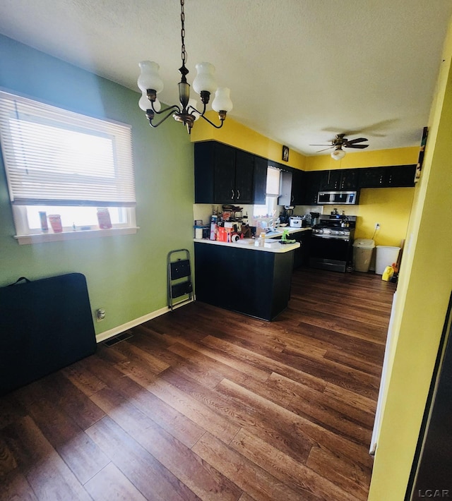 kitchen featuring dark hardwood / wood-style flooring, decorative light fixtures, stainless steel appliances, and kitchen peninsula