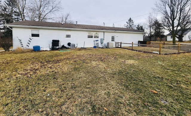 rear view of property featuring a yard and central AC unit