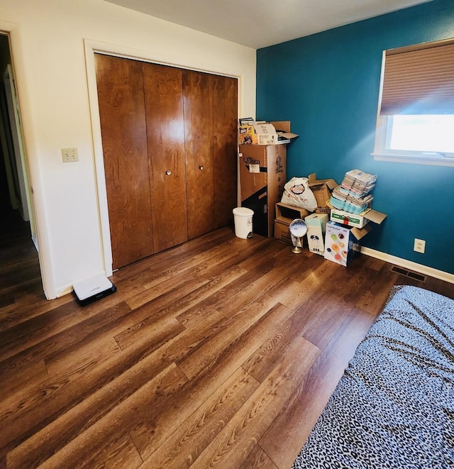 bedroom with dark wood-type flooring and a closet