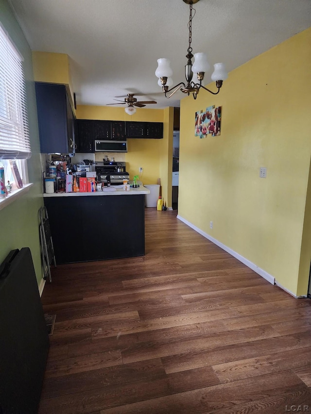 kitchen with ceiling fan with notable chandelier, dark wood-type flooring, kitchen peninsula, and appliances with stainless steel finishes