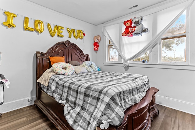 bedroom with dark hardwood / wood-style flooring and multiple windows