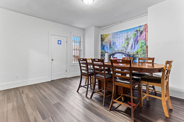 dining room with dark wood-type flooring and a textured ceiling