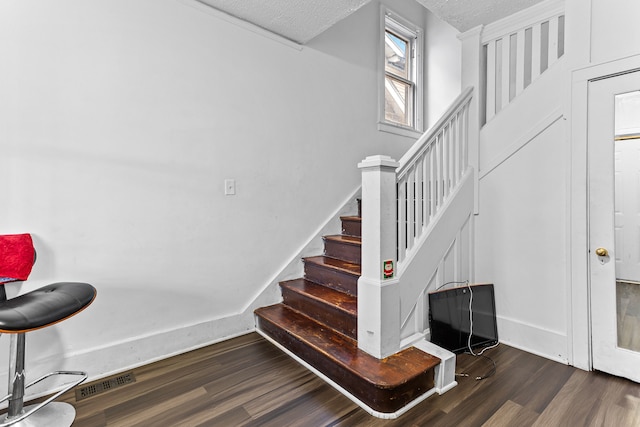 stairs featuring wood-type flooring and a textured ceiling