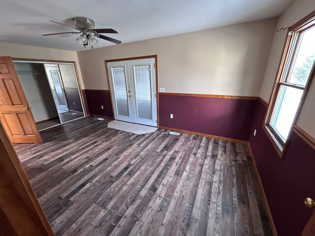 unfurnished bedroom featuring a closet, dark wood-type flooring, french doors, and ceiling fan