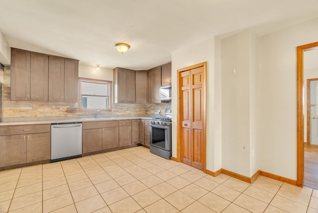 kitchen featuring tasteful backsplash, appliances with stainless steel finishes, sink, and light tile patterned floors