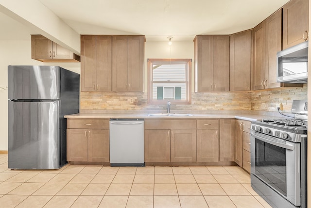 kitchen featuring light tile patterned flooring, appliances with stainless steel finishes, sink, and backsplash