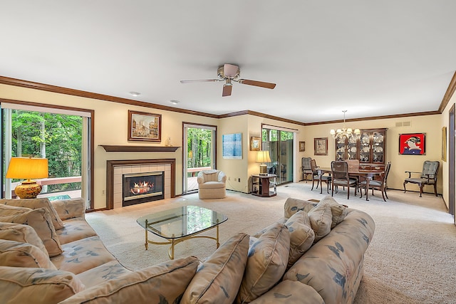 carpeted living room with ornamental molding, ceiling fan with notable chandelier, and a tile fireplace