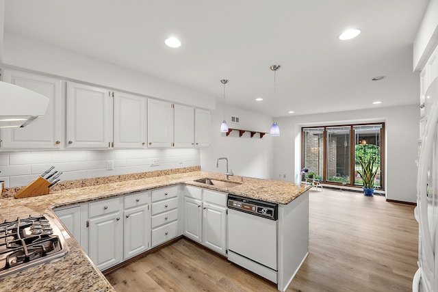 kitchen with white dishwasher, sink, white cabinetry, and kitchen peninsula