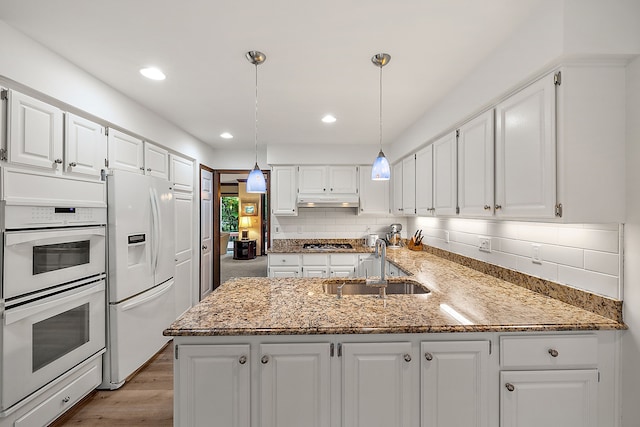 kitchen with pendant lighting, white cabinetry, sink, kitchen peninsula, and white appliances