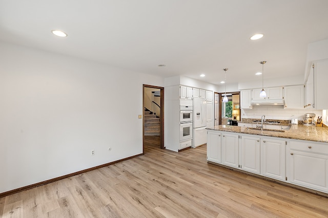 kitchen featuring sink, tasteful backsplash, light stone countertops, white cabinets, and light wood-type flooring