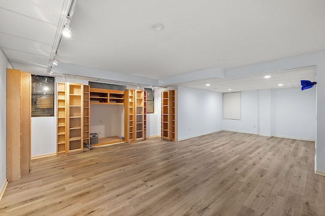 basement featuring rail lighting and light hardwood / wood-style floors